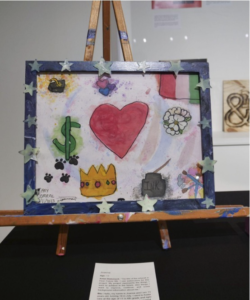 A painting with a white box and a blue border. Inside the white box are images including a heart, the dollar symbol and a crown.