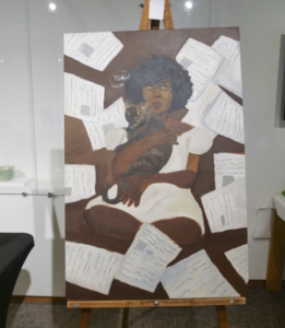 A painting with a brown background, a Black woman in a white dress and afro holds a brown cat. Papers surround her body.