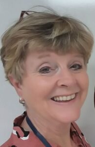 Image of teacher Linda Robinson, a woman with short blonde hair with glasses on her head