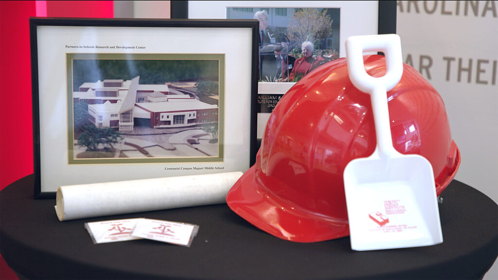 A table featuring a red hard hat, a white sand shovel and a picture of the Friday Institute.