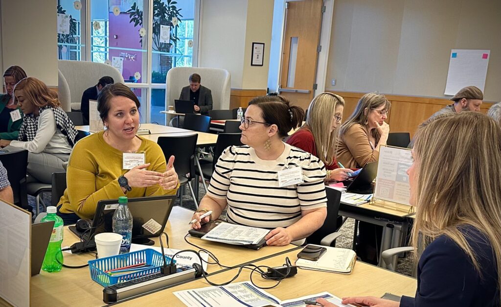 A group of educators sit around a table having a discussion