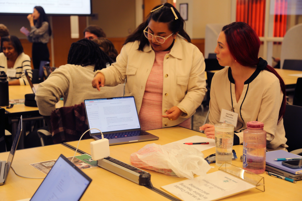 Two people speak while looking at a monitor