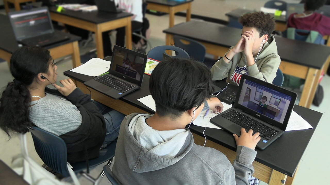3 students sitting at a table working on an educational game