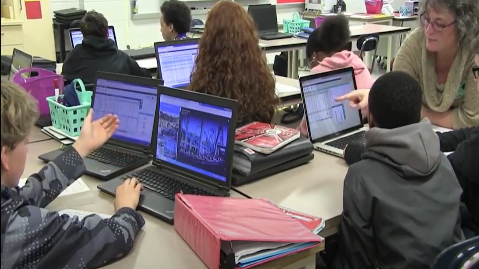 Professor Hollylynne works with students in a classroom working on laptops