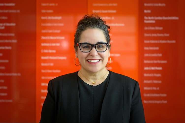 Headshot of Krista Glazewski, a woman with dark brown hair in a bun who is wearing a black blazer and shirt