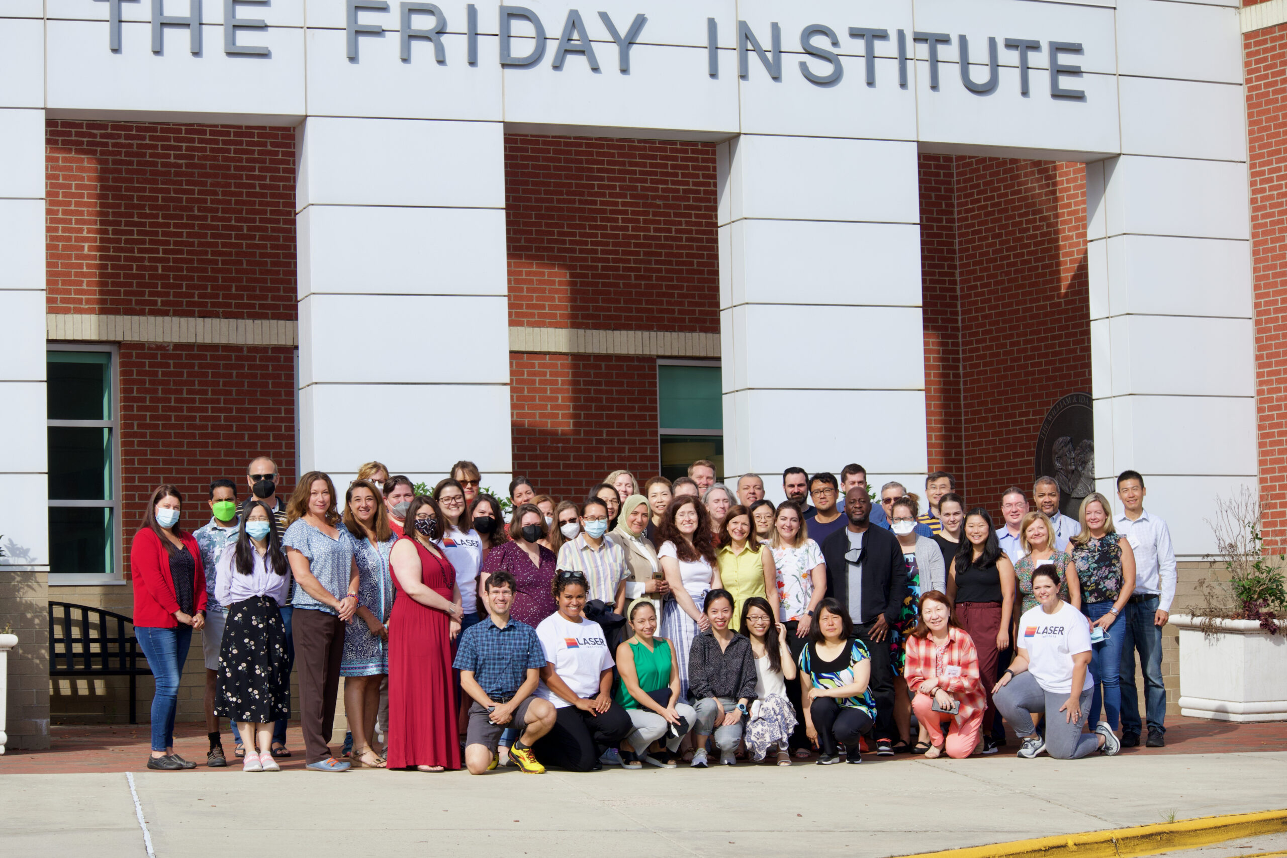 A group of people pose in front of the Friday Institute building