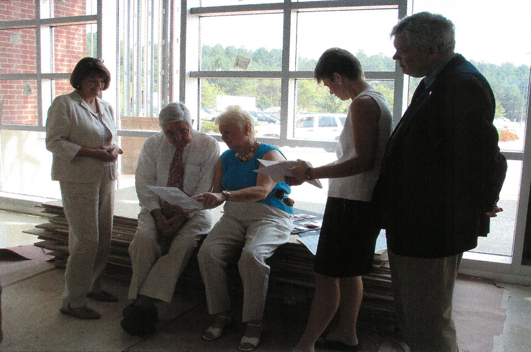 People sit in a construction shot hovering around the blueprints for the site