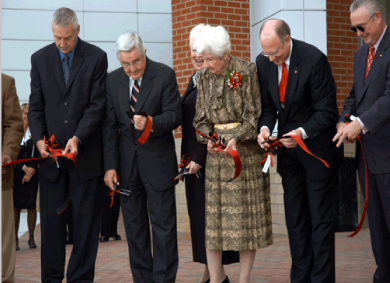 A line of people cut a red ribbon across their waists