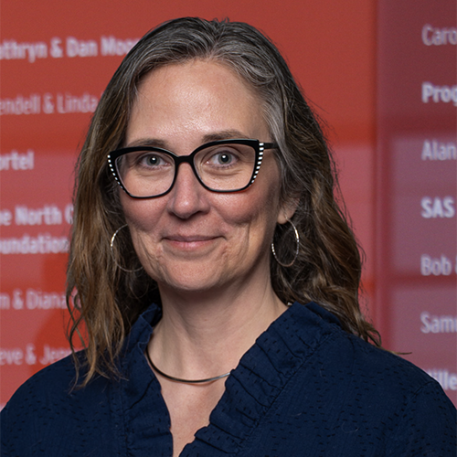 Headshot of Amy Walter, a woman with glasses in front of a red and orange background