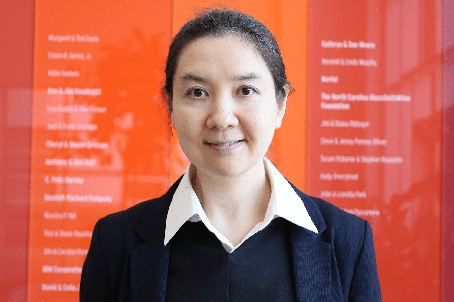 Headshot of Fei Fei Han, a woman with dark brown hair pulled back, a white collared shirt and a navy jacket and vest