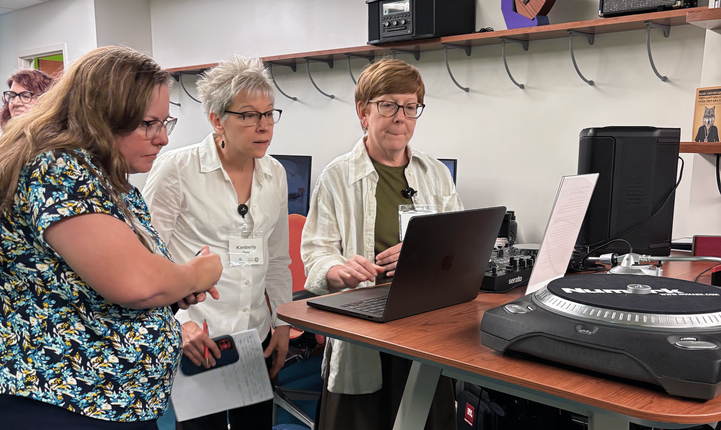 Educators surround a laptop in a studio classroom